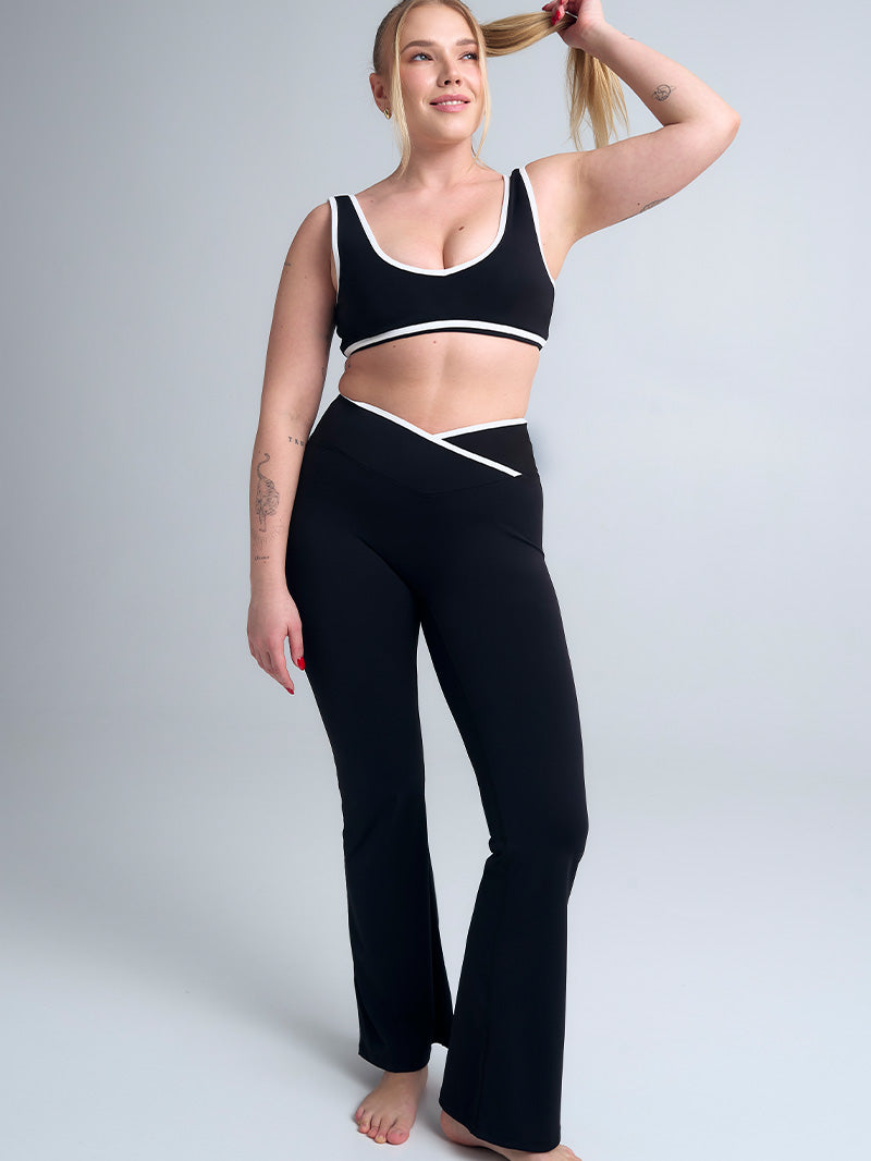 Czarny komplet JOYINME Dual Essence prezentujący harmonijne połączenie stanika i spodni. Biała lamówka na staniku współgra z dekoracyjnym wykończeniem na biodrach, tworząc elegancką, sportową stylizację.