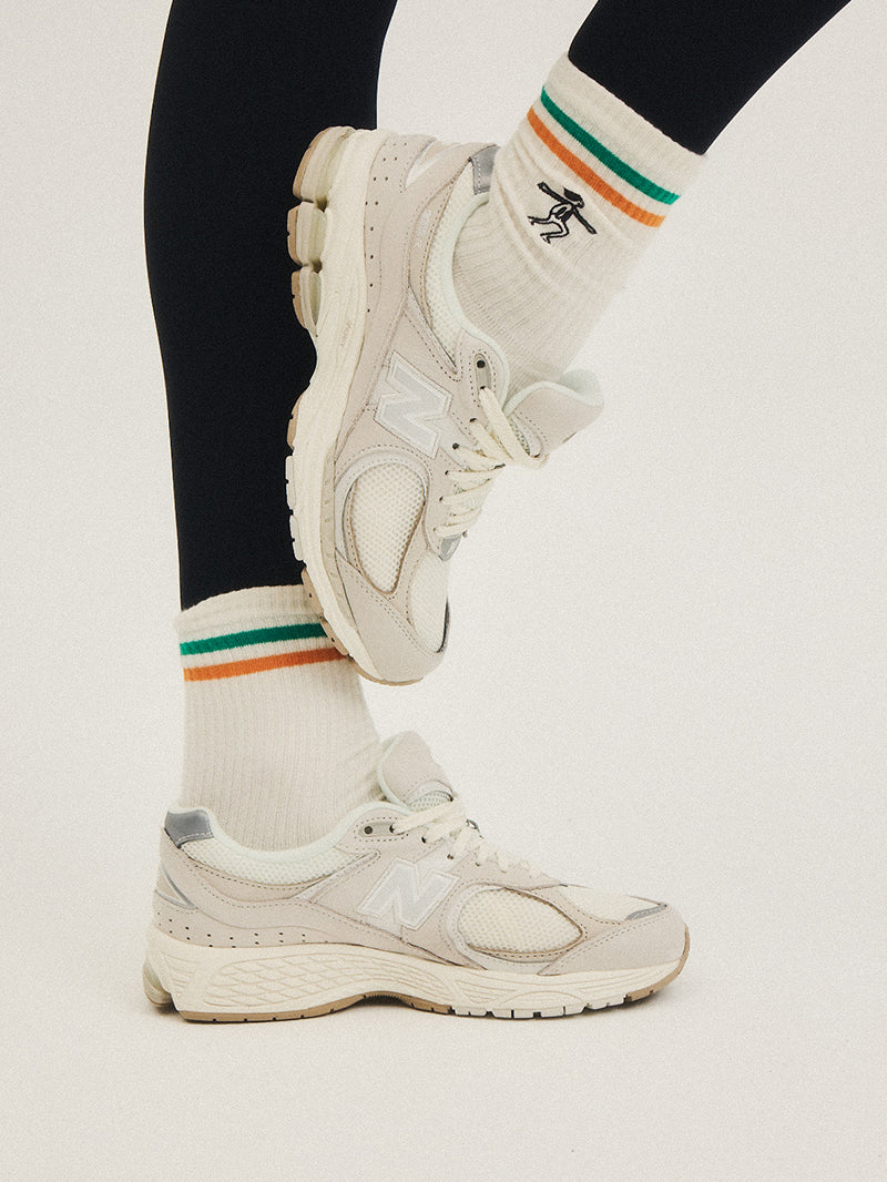 Białe skarpetki do jogi z kolorowymi paskami i haftem joginki - połączenie z jasnymi butami i czarnymi legginsami