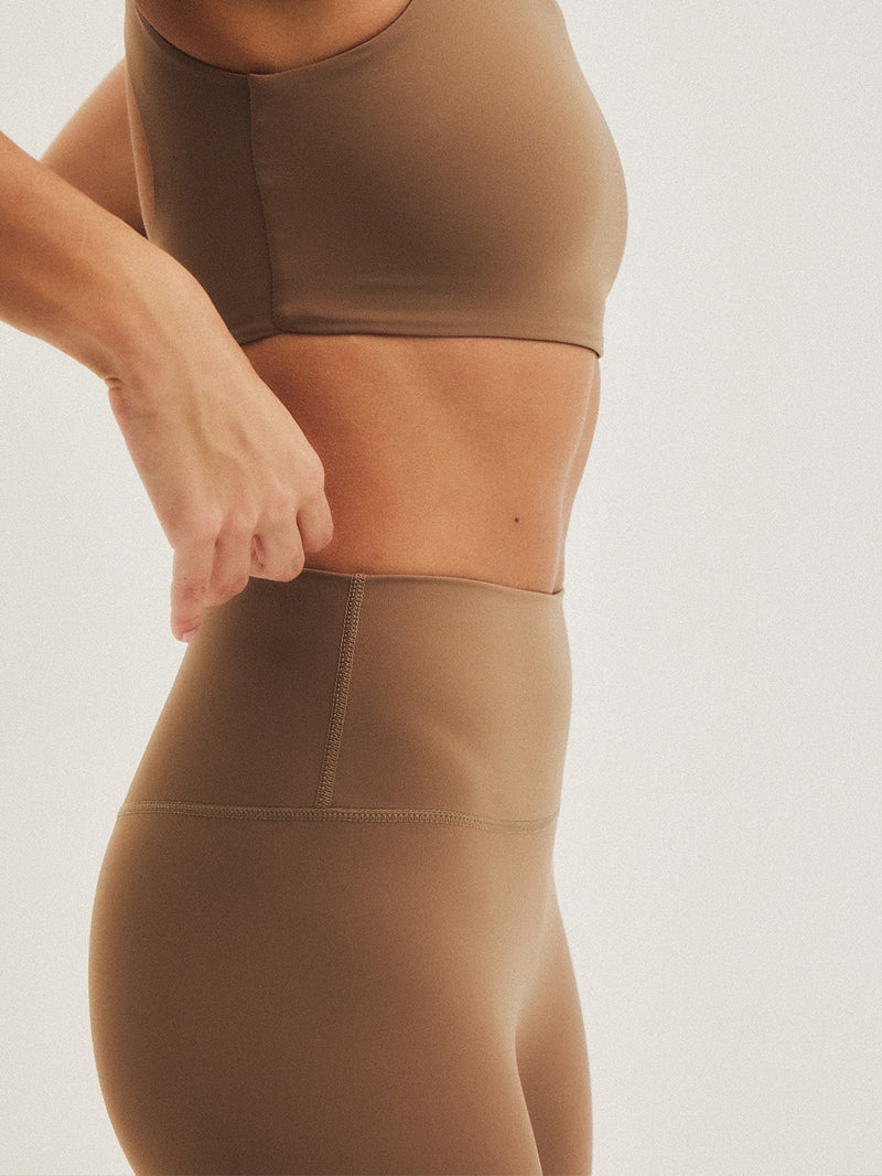 Modelka w brązowych legginsach do jogi z wysokim stanem - widok z boku