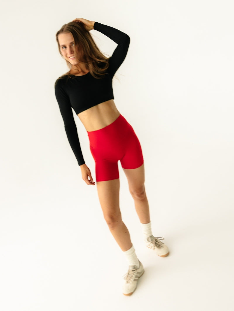 Czerwone damskie spodenki do jogi - outfit z czarnym crop topem z długimi rękawami