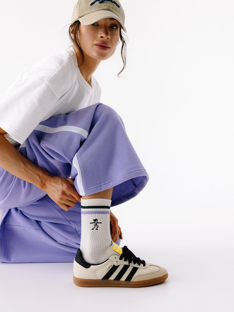 Fioletowe bawełniane spodnie z lampasem - widok na szerokość nogawki w połączeniu z wysokimi skarpetkami i trampkami