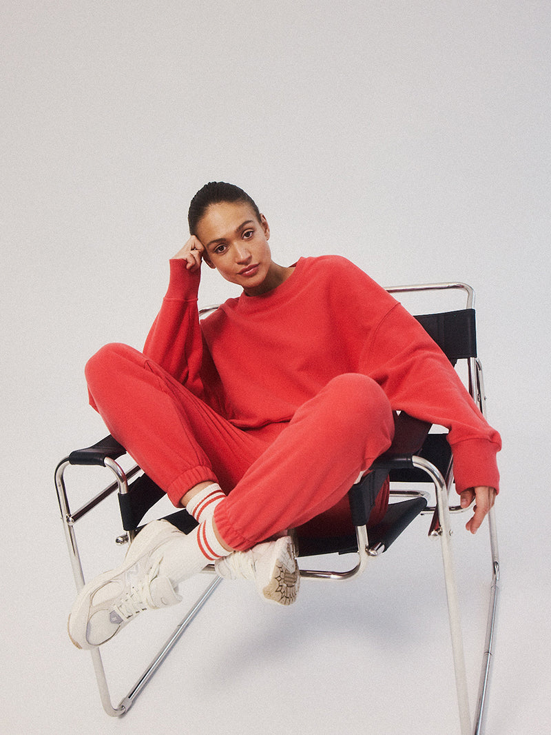 Luźne bawełniane spodnie dresowe, czerwone KIND - modelka podczas siedzenia na krześle