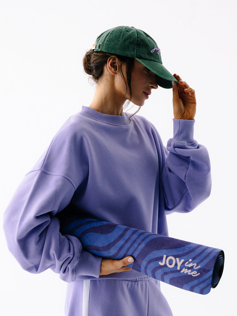 Niebieska antypoślizgowa mata do ćwiczeń jogi 3 mm z grafiką surferki - modelka w szerokiej bluzie i czapce z daszkiem z matą pod ręką